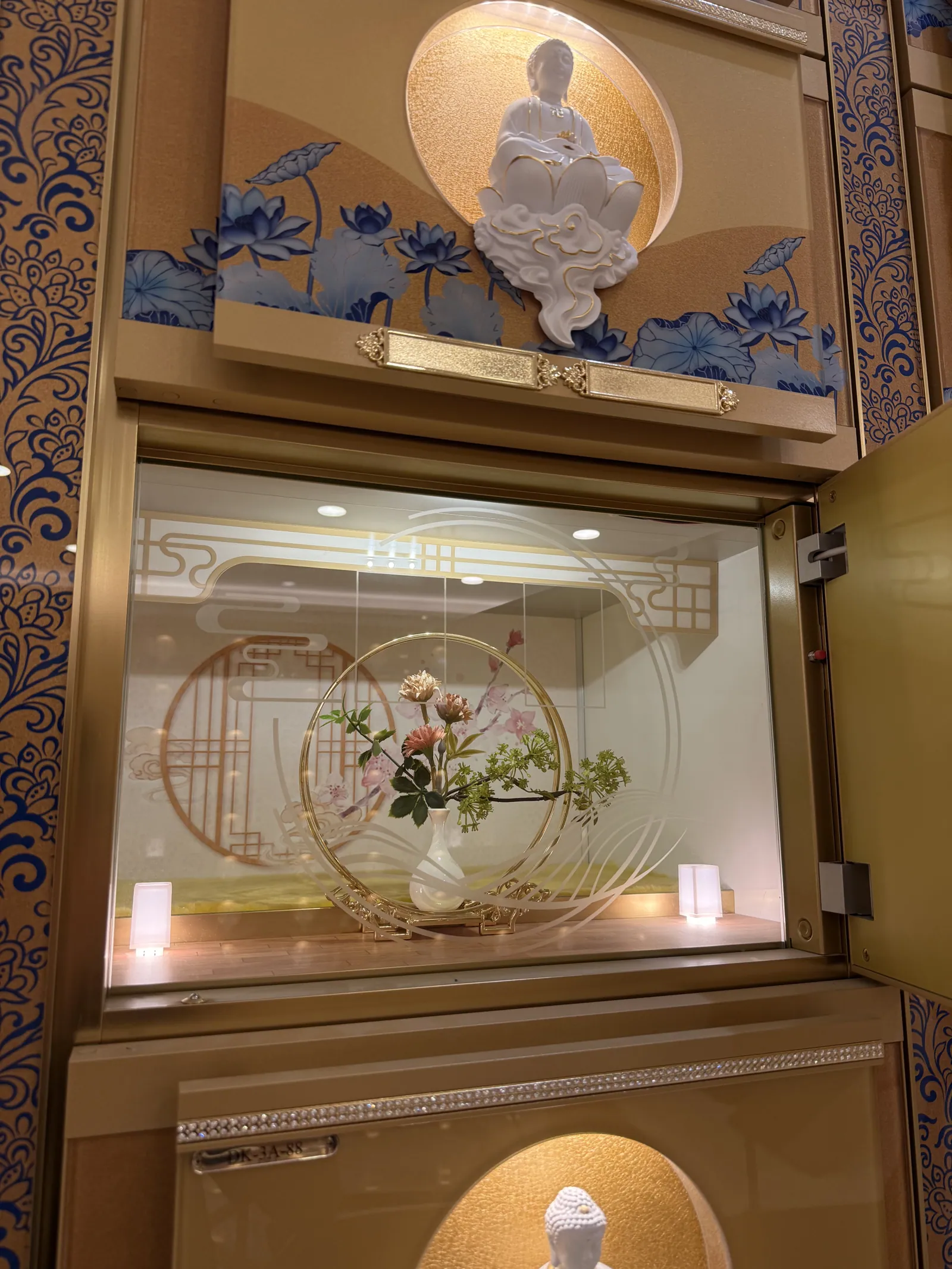 An opened display case holding a flower arrangement and candles