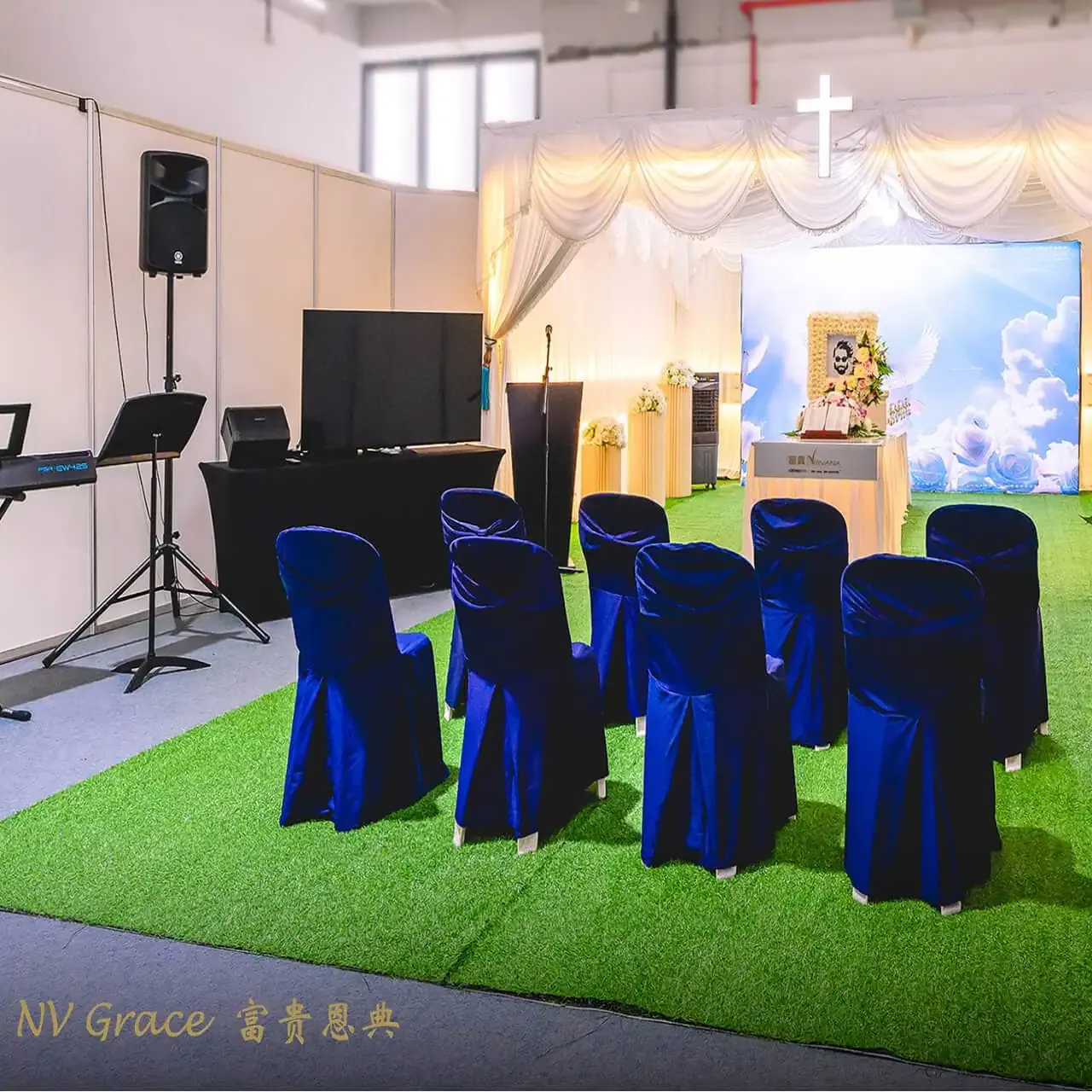 A Christian service hall set with a cross above the altar and rows of covered chairs