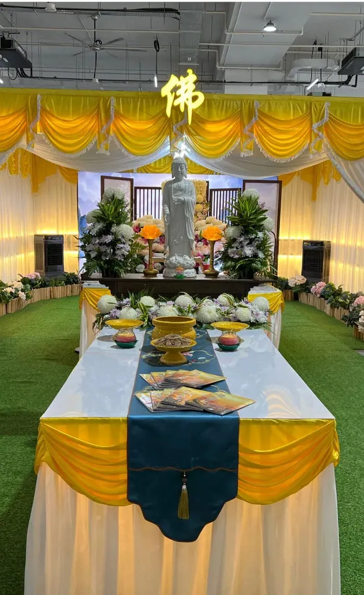 A memorial setting with gold drapery, an offering table and a character banner