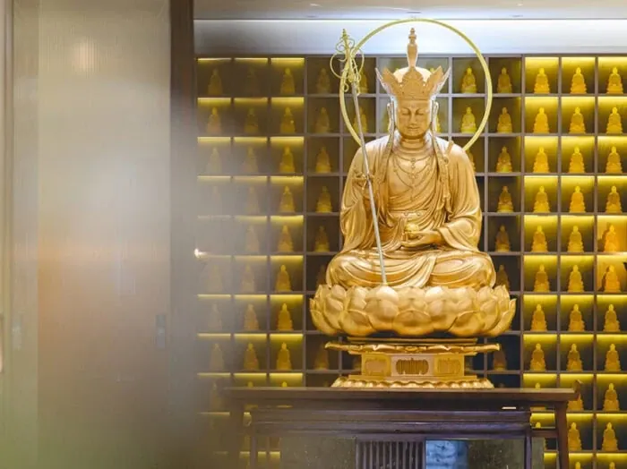 A gilded seated figure enshrined before a wall of gold niches