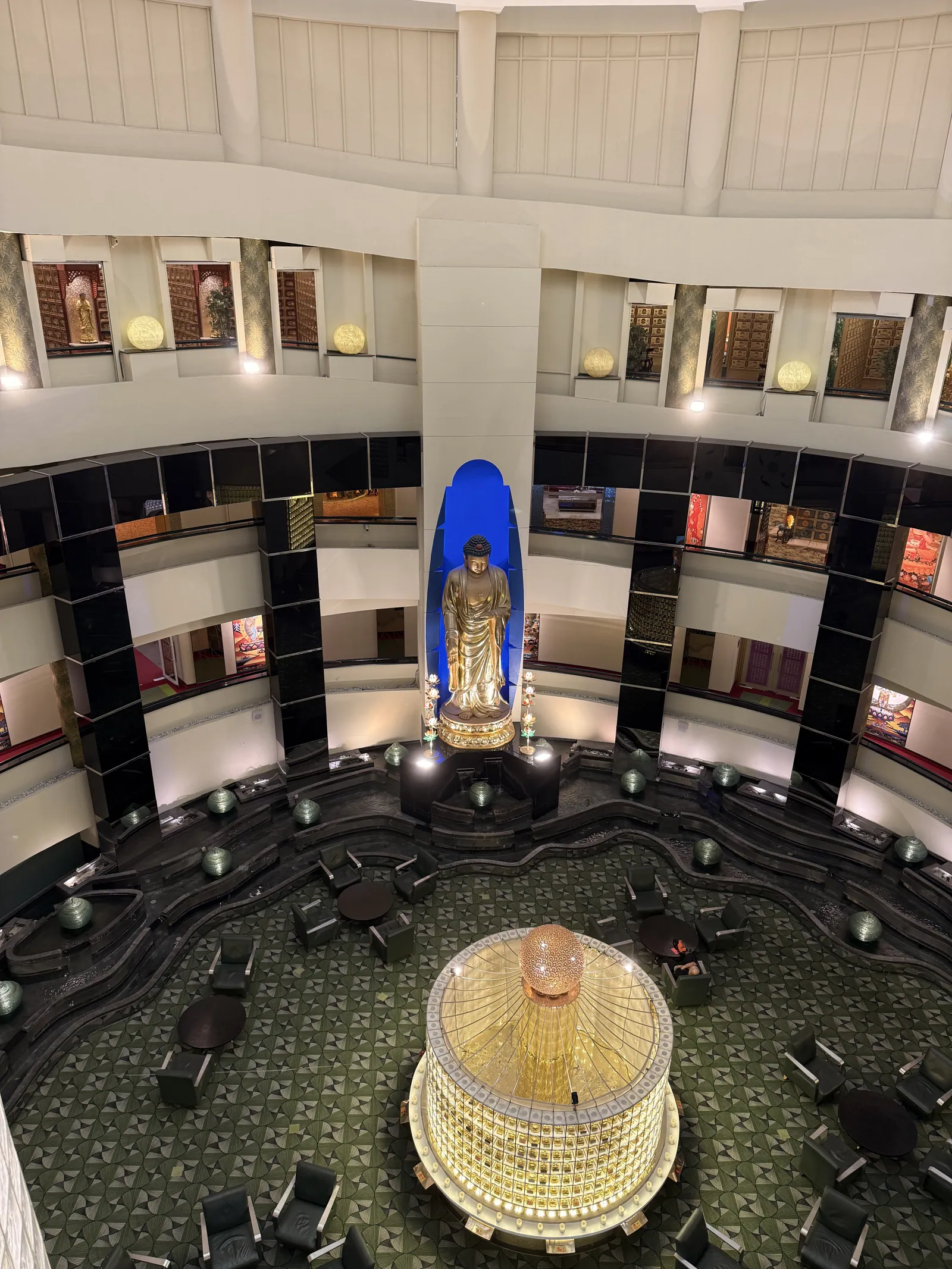 A circular hall of dark niches around a blue-lit Guanyin figure and a crystal centrepiece